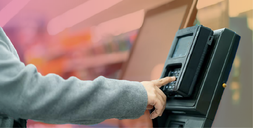 A person using a self-checkout machine in a retail store, interacting with the payment keypad.