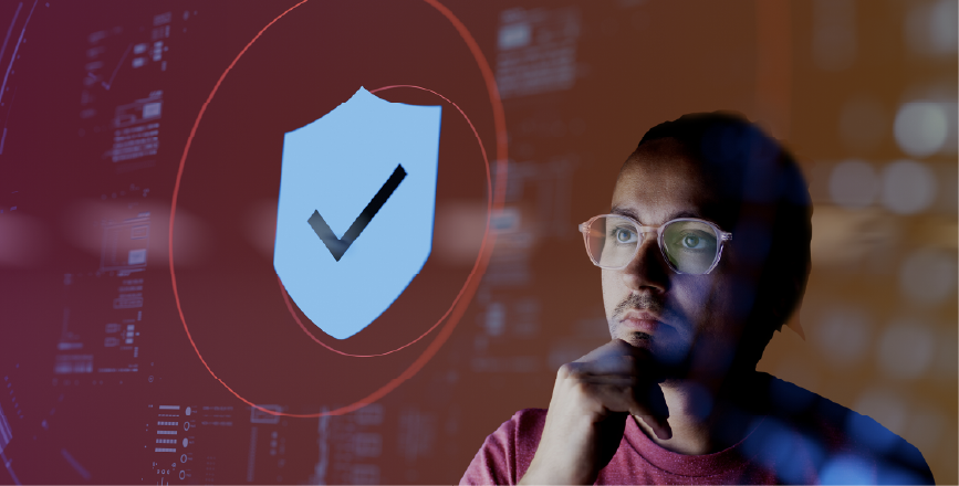 A person with glasses pondering in front of a digitally illustrated security shield and checkmark, symbolising cybersecurity.