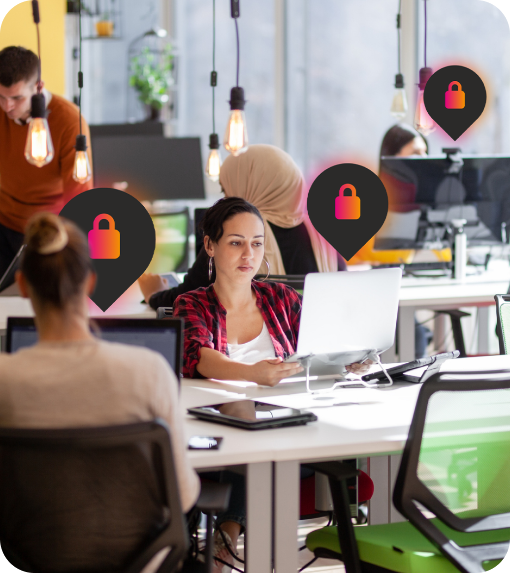 A woman focused on her laptop in a modern office space, surrounded by other people working, with icons representing privacy or security.