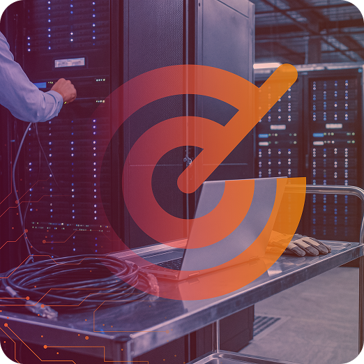 A person adjusting equipment on a server rack with a laptop and cables on a cart in a data centre setting.