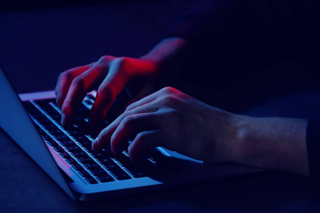 Professional hacker with laptop sitting at table, closeup